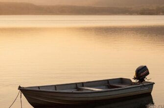 Вид на лодку с электромотором на спокойном озере во время заката.